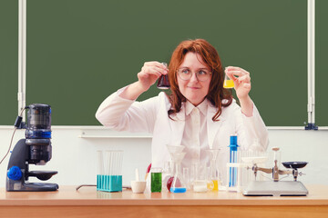 Chemistry teacher looks at reagent bubbles while sitting at a desk at school. Chemistry lesson with...
