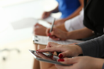 Close up of group of people sitting in a row and filling out interview forms