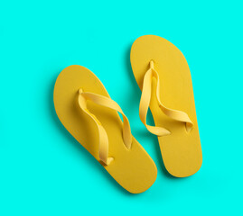 Yellow beach slippers on a turquoise background. summer concept