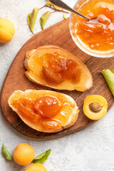 Toast of bread and apricot jam with slices of fruit and fresh apricots on a table top view. Toasts with jam close-up. Tasty sweet breakfast.