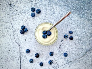 Fresh blueberries and yogurt against a natural stone granite textured background. Healthy summer berries full of antioxidants. Food on the kitchen counter.