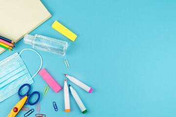 Useful for the return to school with mask and disinfectant gel on a blue background. Copy space.