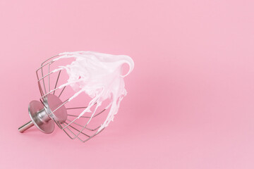 Blender rod with pink meringue on a pink background. Kitchen concept.