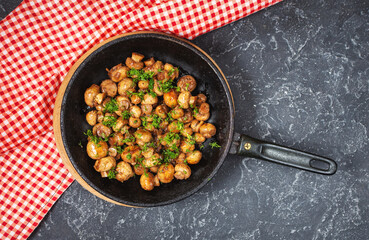 Delicious fried mushrooms in pan on stone table, top view