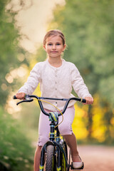Fototapeta na wymiar girl rides a bicycle in a summer park