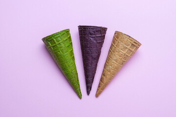 Top view of purple, green and brown waffle horns filled with cottage cheese in chocolate glaze in the center on pink background, flat lay. Waffle dessert, idea concept, top view, close up, copy space