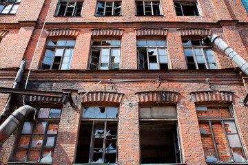 Wall of abandoned building with broken windows. Old red brick house.