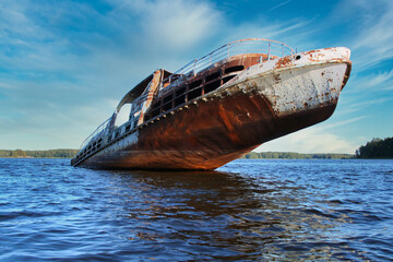 An old rusty wrecked ship is sinking in a lake. Passenger ship sinking in the water.