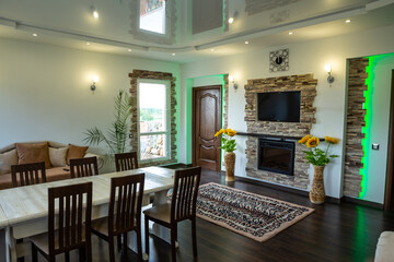 Living room of country house with long table, big sunflowers in floor vases and cozy sofa. Green light.
