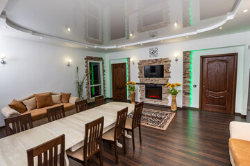 Living room of country house with long table, big sunflowers in floor vases and cozy sofas. Evening light.