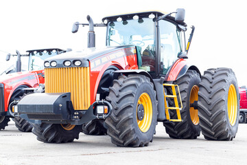 Obraz premium Large agricultural tractor on a white background. Equipment for cultivating the land. Close-up.