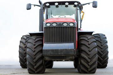 Large agricultural tractor on a white background. Equipment for cultivating the land. Front view. Close-up.
