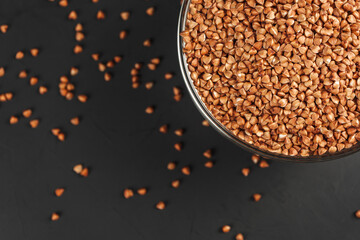 Buckwheat in a glass plate and scattered on the black table. The view from the top.