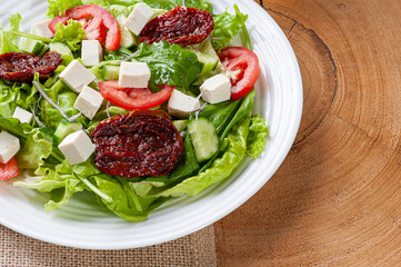 .Green salad with lettuce, arugula, cucumber, cheese and sun-dried tomatoes.