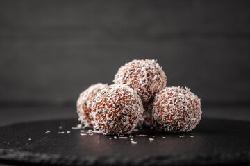 Sweets made of dates and coconut shavings without sugar on a slate Board
