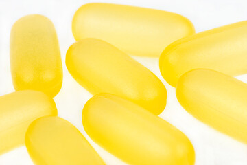 Macro shot of yellow gelatin capsules, isolated on a white background.