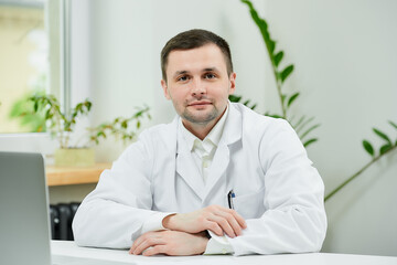 A kind caucasian doctor in a white lab coat is sitting arms crossed in a hospital. A therapist near...