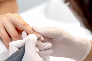 Obraz na płótnie Canvas Manicure master uses an electric nail machine to remove nail polish hands in nail salon