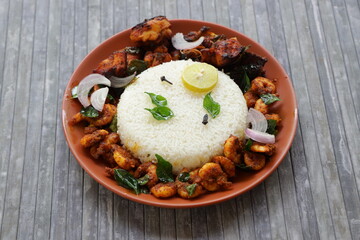 Biryani rice or Geera rice with chicken fry and prawns fry as side dish arranged in a terraccotta earthen plate with grey texture background