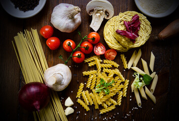 Variety of pasta and other ingredients on wood