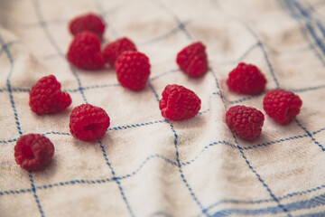 Pile of fresh raspberry in a white plate top view of red berries on the white napkin. Summer feeding concept. Summer berries concept. 