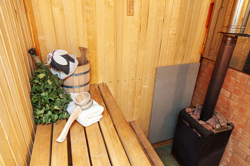Fototapeta na wymiar Interior details Finnish sauna steam room with traditional sauna accessories basin birch broom scoop felt hat towel. Traditional old Russian bathhouse SPA Concept. Relax country village bath concept
