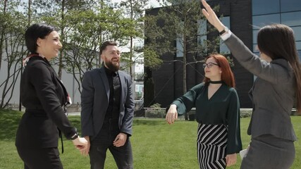 Successful business team giving a high five together. Business building background. Staying outside.