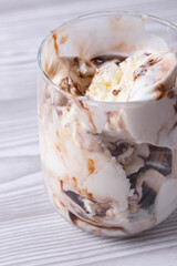 delicious creamy milky vanilla ice cream with caramel and chocolate addings in a glass container on the light rustic background