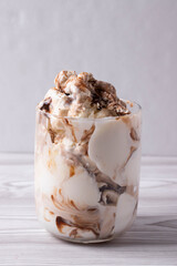 delicious creamy milky vanilla ice cream with caramel and chocolate addings in a glass container on the light rustic background