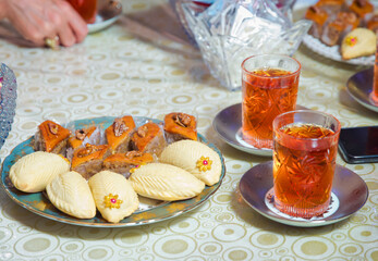 Baklava and Shekerbura blue plate . Glass of Azerbaijan tea isolated on white . Cup of tea isolated on white tablecloth . Shekerbura with nuts and honey.