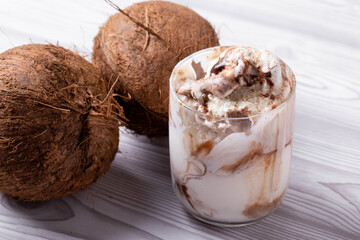 delicious creamy milky vanilla ice cream with caramel and chocolate addings in a glass container on the light rustic background