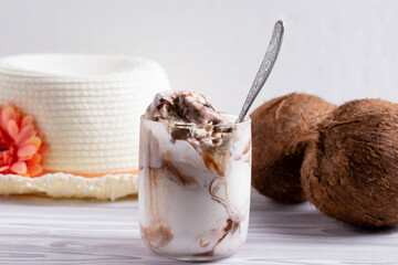 delicious creamy milky vanilla ice cream with caramel and chocolate addings in a glass container on the light rustic background