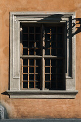 Old window with a wooden frame and glass on the facade of the house with brown stucco. Lviv, Ukraine.