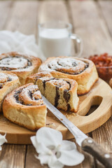 Basket of homemade buns with jam, served on old wooden table with walnuts and cup of milk