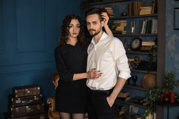Couple gently hugs each other and looks at the camera. Cropped stylish portrait of trendy man and curly woman in photo studio. Wife and husband in expensive suits and hairstyle. Mr after barber shop