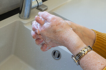 To wash the hands with soap in a bathroom