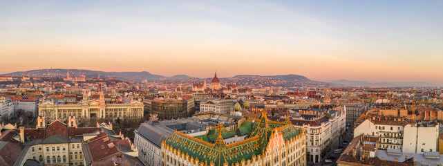 Panoramic Aerial drone shot of art nouveau rooftop postal bank in Budapest dawn with Parliament view