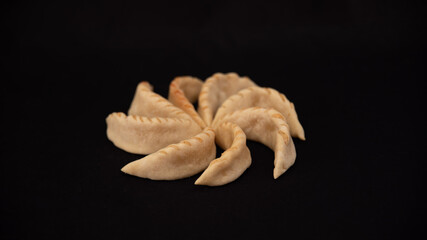 
Moroccan gazelle horns, delicious homemade pastries, arranged in a spiral, on a black background