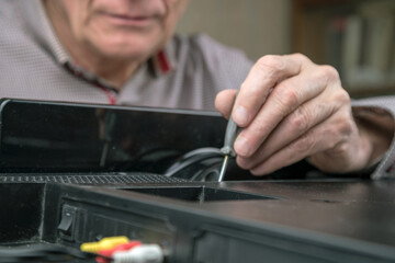 aged person in shirt unscrews television back cover detail repairing set at home