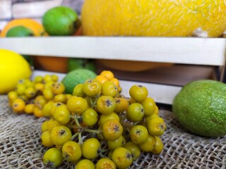 Fruit and berry still life yellow oval melon orange lemon red apple green unripe walnuts and yellow rowan in a wooden box on the kitchen table