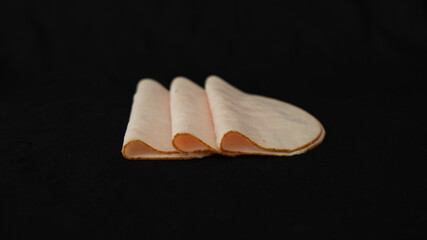 
Trio of poultry ham slice, folded in half, on a black background