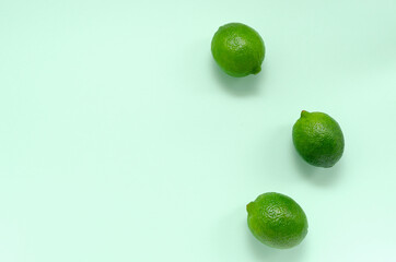 Three fresh juicy bright limes on a gentle mint light background with place for text. citrus vitamin C healthy eating and minimal lifestyle. blank for postcards banner and menu