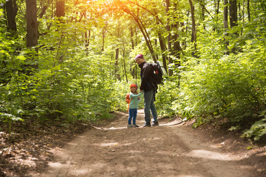 Father And Child Daughter With Backpack Hiking In Forest. Social Distancing. Digital Detox. Staycations, Hyper-local Travel,  Family Outing, Getaway, Natural Environment