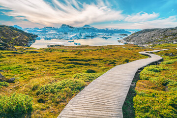Hiking trail path in Greenland arctic nature landscape with icebergs in Ilulissat icefjord. Photo of scenery ice and iceberg in Greenland in summer. © Maridav