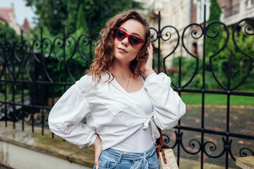 Outdoor street portrait of young beautiful fashionable woman wearing stylish summer accessories in city.