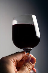 Glass of red wine in man's hand, preparing for cheers