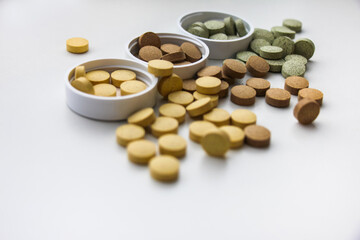 Supplements are scattered on the surface of the table close-up. White background. Vitamins and food additives help take care of health, have natural plant components and healthy nutrients.