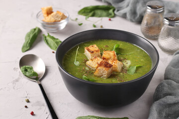 Green spinach puree soup served with croutonsin a dark bowl on a gray concrete background, Closeup, Space for text