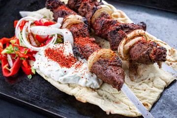 Traditionelle griechische Souvlaki Lamm Grillspieße mit Paprika, Zwiebel und onion und Zaziki angeboten als close-up auf einem rustikalen Metall Tablett 