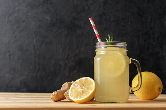 Jar with ginger water and lemon on wooden table with copy space.